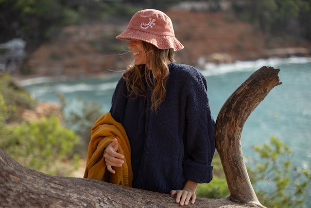 A woman in a pink hat sitting on a tree branch